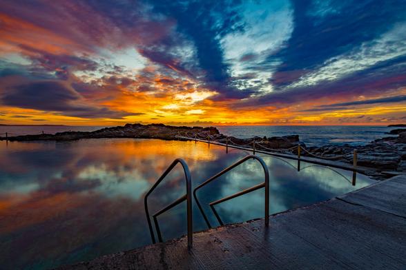 Blowhole Point Ocean Pool is located in Kiama in South Coast NSW Australia. This photograph was taken at sunrise, looking out over the Pacific Ocean as a beautiful sky coloured up and reflected in the calm pool water.