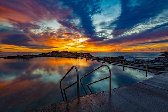 Blowhole Point Ocean Pool is located in Kiama in South Coast NSW Australia. This photograph was taken at sunrise, looking out over the Pacific Ocean as a beautiful sky coloured up and reflected in the calm pool water.