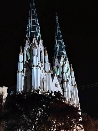 Lights play off the spires of a church at night in Savannah GA