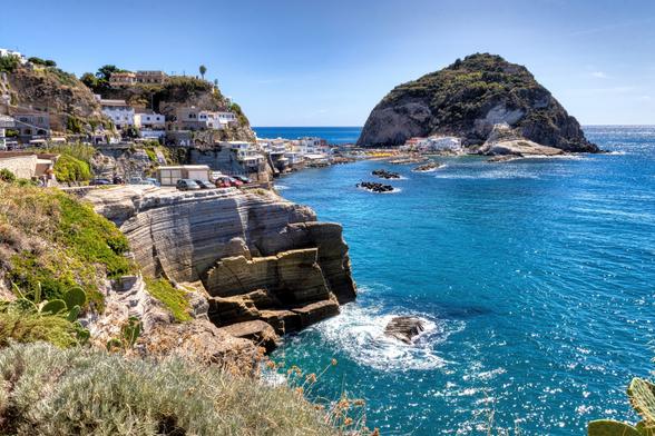 una scogliera sull'isola di ischia, con un piccolo monticello antistante. La scogliera è collegata al monte da una lingua di sabbia.