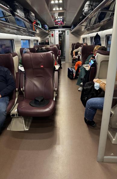 Interior of an iryo Frecciarossa 1000 showing the plush leather seats in “Singular” class. My hat is on the aisle seat, one of two. There is about 2m of visible floor space in front of the seat.