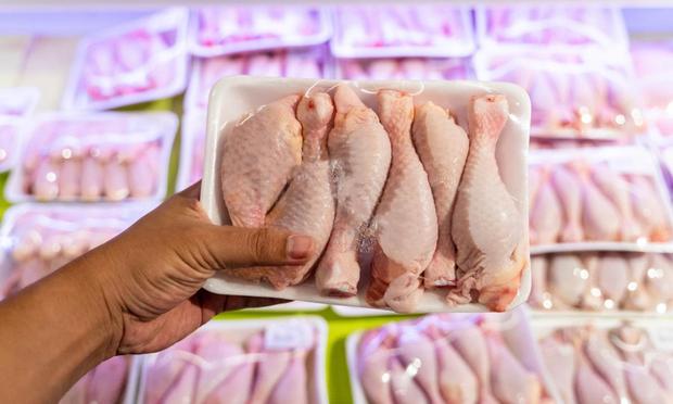 Una persona sostiene una bandeja con pollo en un supermercado. (Yasser Chalid)