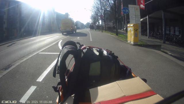 Blick über den "Bug" eine beladenen Lastfahrrades. Voraus ein Hochbord-Fahrradweg. Auf der Fahrbahn (KFZ-Fahrspur) hält ein Zustellfahrzeug