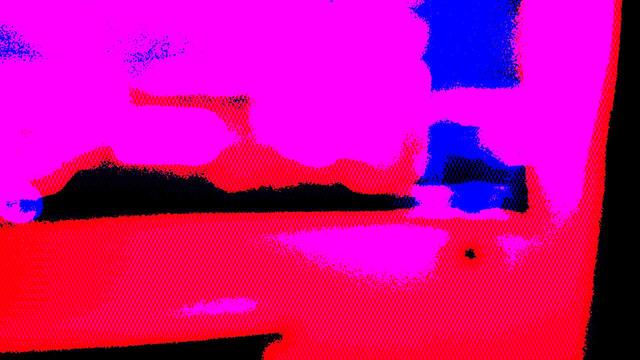 The entire image consists of blurry shapes in vibrant red, magenta and dark blue. The background is black. Nothing meaningful can be made out in the shapes.
