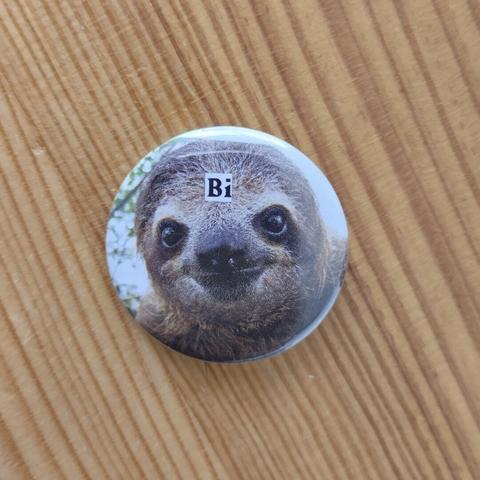 Badge avec le portrait d'un paresseux. Il y a écrit "Bi" sur son front.