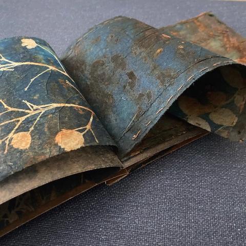 Image of sewn book pages made from cyanotype printed teabags covered in rust.