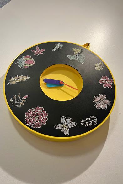 una foto de un reloj de pizarrón con dibujos de flores de la baraja japonesa Hanafuda