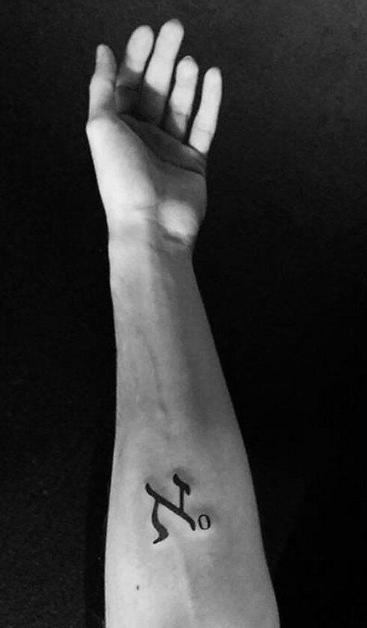 Black and white image of hand and forearm with the Hebrew letter Aleph subscript 0 (mathematical symbol for the Aleph Null) tattooed on the inside of the forearm.
