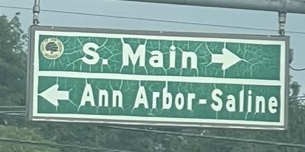 Weathered street sign show S. Main street to the right, and Ann Arbor-Saline road to the left