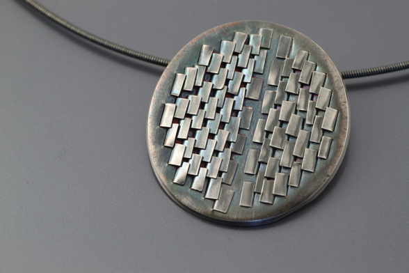 Round silver pendant with relief.