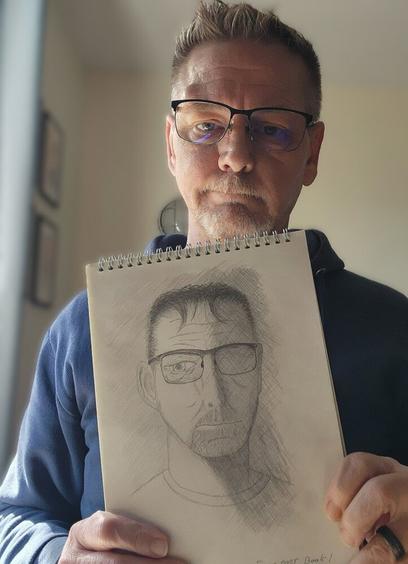 San Diego artist Steven Preston, holding his sketchbook showing a self portrait done in pencil.