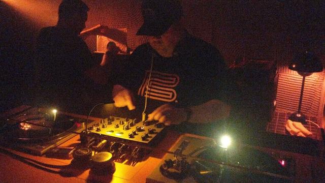 DJ playing vinyl records on two decks with a rotary DJ mixer