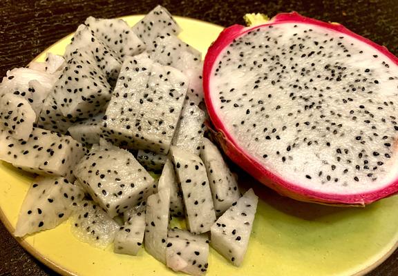 One half of the Dragon fruit is cut in dice shape, and the other half is not.