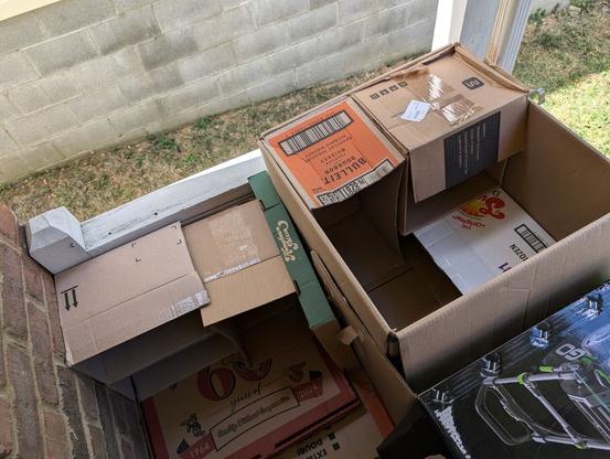 more boxes in boxes, on a front porch overlooking dry summer grass and the neighbor's cinderblock foundation
