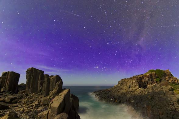 Location details: Kiama, Australia
The dramatic Bombo Quarry at Kiama, bathed in the ethereal glow of an evening sky ablaze with stars.  The rugged basalt columns stand sentinel against the inky twilight, their textures and forms highlighted by the soft, almost magical light.  The gentle movement of the waves at the base of the cliffs creates a mesmerizing effect, adding a sense of tranquility to the scene.  The vibrant purple hues of the night sky, dotted with countless stars, create a truly captivating and awe-inspiring landscape.

Technical information:
* Exposure: 30.0 sec at ƒ/3.5
* Shutter speed: 30.0 sec
* Aperture: ƒ/3.5
* Focal length: 10 mm
* Lens: EF-S10-22mm f/3.5-4.5 USM
* ISO: ISO 1600
* Camera model: Canon EOS 7D Mark II
* Camera make: Canon
* Post processing: DxO PhotoLab 8.2.1