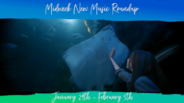 In a distressed frame (top and bottom bars only, blue to light green vertical gradient), a young woman (Moonbyul of Korean pop girl group MAMAMOO) faces away from the camera, her right arm raised up and out towards the glass of the aquarium tunnel above her head where a large ray is swimming close to the glass, other vague shapes of fish semi-visible in the depths of the enclosure. Header text reads Midweek New Music Roundup, bottom text reads January 29th - February 5th.