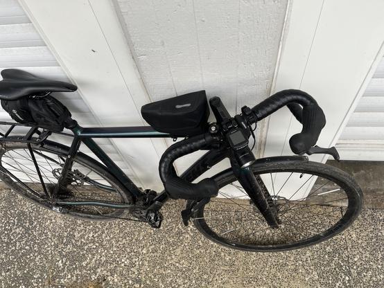 Top-down picture of road bike after being hit by a car. Handlebars folded in and the frame is cracked.