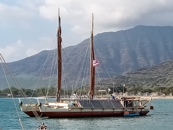 Hokule'a in Poka'i Bay in Oahu, with the mountains in the distance behind.