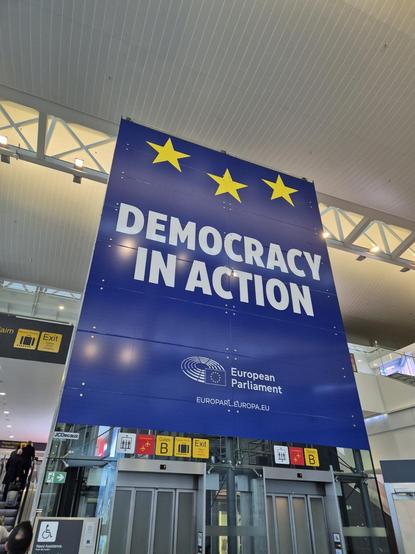 Fotografía de un cartel del parlamento europeo en el aeropuerto de Bruselas: DEMOCRACY IN ACTION