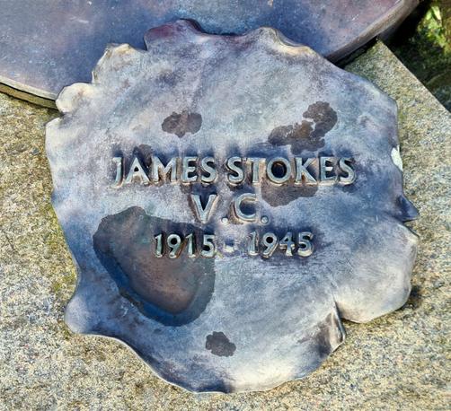 A bronze representation of a fallen petal with the words James Stokes V.C. 1915 -1945 on it.