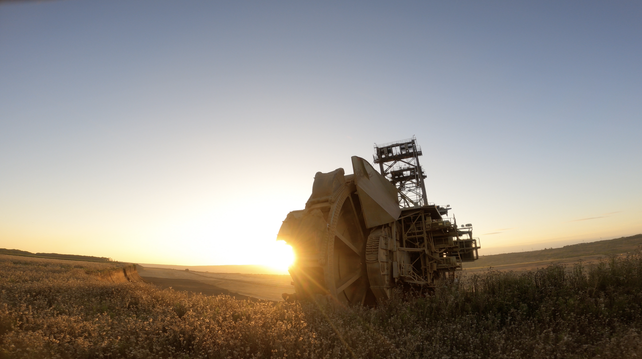 Photo of a bucket wheel excavator with the sunset in the background.