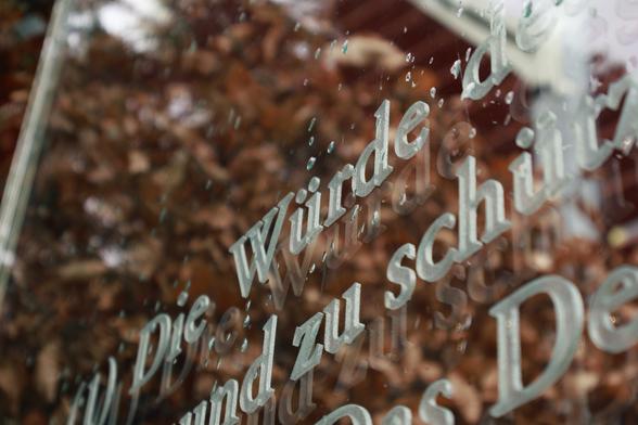 Makroaufnahme einer Glastafel mit Art. 1 GG
Im Zentrum steht das Wort "Würde"
