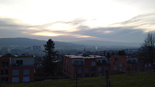 Hell erleuchteter, gelblicher Himmel über ein paar grauen Wolken am Horizont. Darunter ein städtisch besiedeltes Tal. (Ja, Zürich und das Limmattal.)