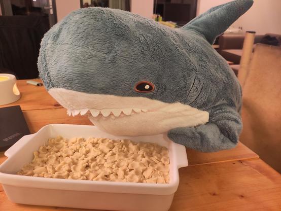 A Blåhaj cuddly shark sitting at the table with one fin on a oven dish and looking at it. Visible in the oven dish are crumbles dough.

Hapi looks really happy with the result, they look almost smug. And fair, Hapi did really well!