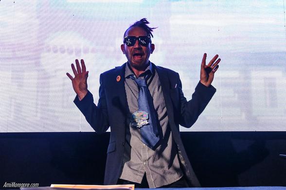 One Hit Kill - a man in a tie and pixelated sun glasses throwing his hands up mid performance
