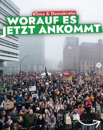 Das Bild zeigt eine Menschenmenge, die eine Demonstration für das Klima durchführt. Die Menschen halten Schilder hoch. Im Hintergrund sind Gebäude im Nebel zu sehen. Über dem Bild steht "Klima & Demokratie" in roten Buchstaben.