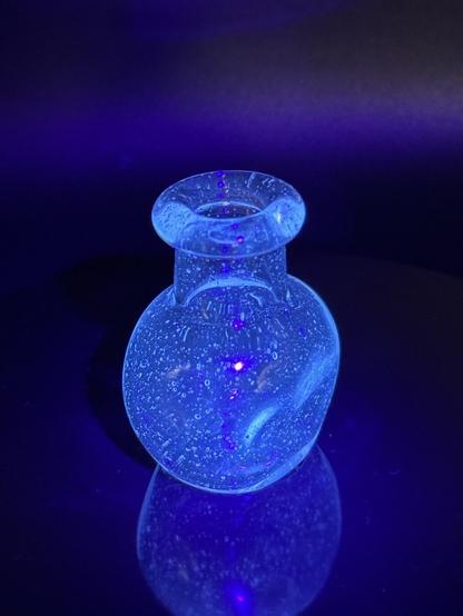 Uv reactive glass bottle, glowing blue under a black light