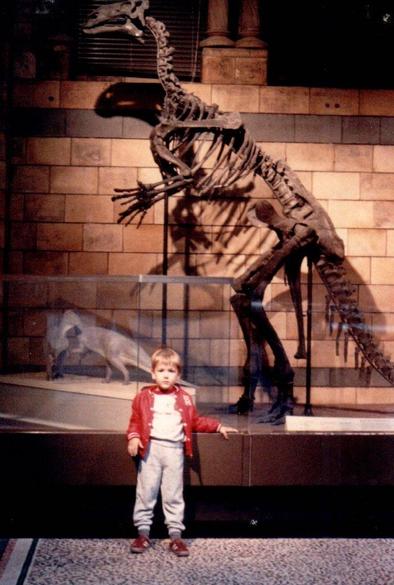 Young boy in front of a dinosaur skeleton.