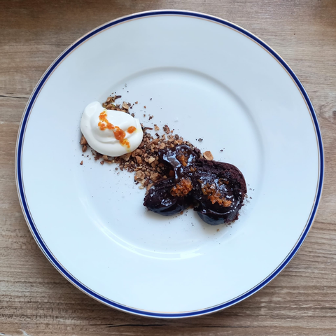 Auf dem Teller wurde eine „Spur“ Nüsse gelegt, links ein Klecks Creme Fraiche und rechts zwei Nocken der Schokolden-Ganache, mit dem Orangenschalen-Öl beträufelt und grobem Meersalz bestreut.