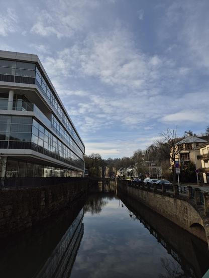 Foto de la rivero Alzeto, en kiu reflektiĝas blua ĉielo kun maldensaj nuboj.