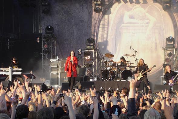 Nightwish esiintymässä Tuskan päälavalla 2004. Kuvan alalaidassa paljon yleisöä takaa päin nähtynä. Lähes kaikilla on kädet ylhäällä osoittamssa suosiota bändille. Kuvassa näkyy kaikki bändin jäsenet. Taustalla on Once-levyn kansikuva lavan korkuisessa lakanassa.