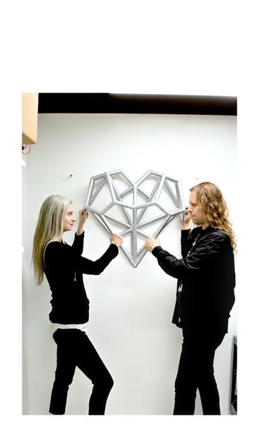 Katherine and Duane pose with a larger than life version of their heart pendant design in their studio.