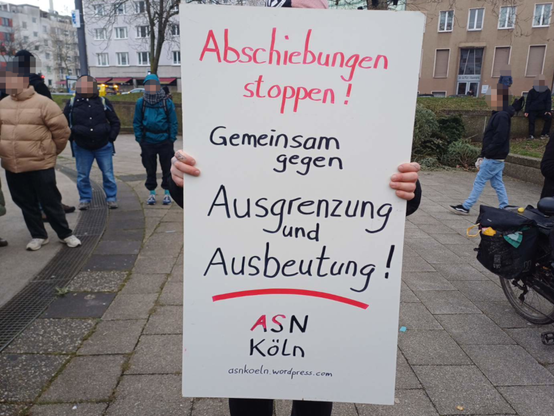 Demonstrant hält ein Schild: "Abschiebungen stoppen! Gemeinsam gegen Ausgrenzung und Ausbeutung" (ASN Köln)