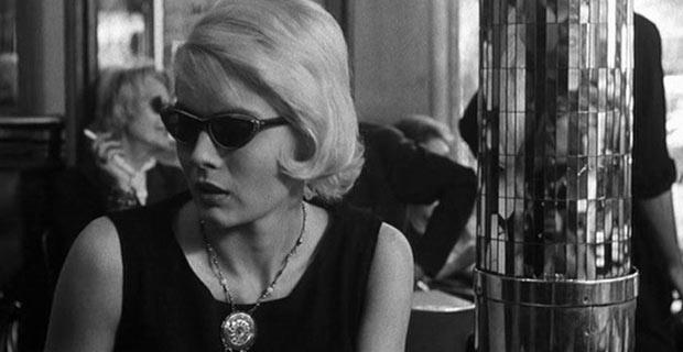 Fotograma de Cleo de 5 a 7 - Agnes Varda - se ve a Cleo, rubia, con gafas de sol, vestido negro, en una concurrida cafetería, inquieta.