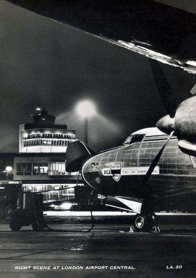 Black and White photo of a plane being worked on as the terminal is in the background