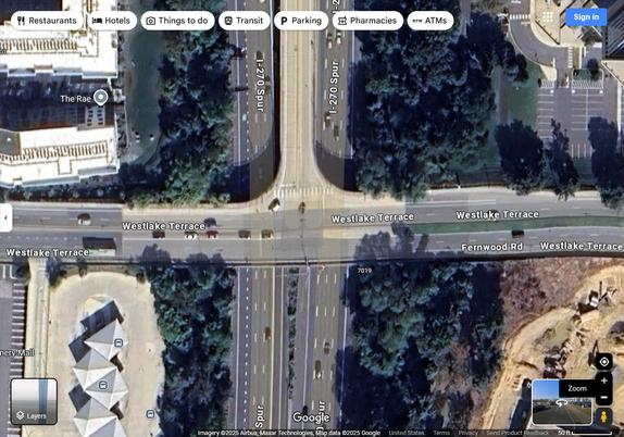 Google satellite hybrid map of a multi-lane road overpass over the I-270 spur. On the north side, there is an on and off ramp in the center of I-270, with a marked crosswalk crossing it. There is a median crossover for the on and off ramp.