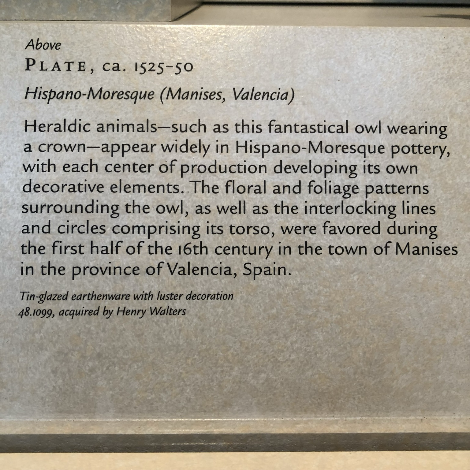 gallery label: “Above PLATE, ca. 1525-50 Hispano-Moresque (Manises, Valencia) Heraldic animals-such as this fantastical owl wearing a crown-appear widely in Hispano-Moresque pottery, with each center of production developing its own decorative elements. The floral and foliage patterns surrounding the owl, as well as the interlocking lines and circles comprising its torso, were favored during the first half of the 16th century in the town of Manises in the province of Valencia, Spain. Tin-glazed earthenware with luster decoration 48.1099, acquired by Henry Walters”