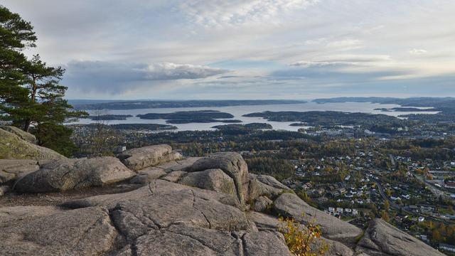 A photo looking off a rocky hilltop at the Oslofjord. The sky is cloudy.