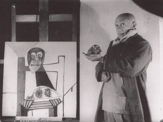 B/W photo by Michel Sima, 1946: Picasso holding his pet owl Ubu in front of a painting featuring his little friend (Owl on a Chair and Sea Urchins, 1946) 1946)  “While Pablo was still working at the Musée d’Antibes, [Michel] Sima had come to us one day with a little owl he had found in the corner of the museum. One of his claws had been injured. We bandaged it and gradually it healed. We bought a cage for him and when we returned to Paris we brought him back with us and put him in the kitchen with the canaries, the pigeons, the turtledoves. We were very nice to him but he only glared at us. Any time we went into the kitchen, the canaries chirped, the pigeons cooed and the turtledoves laughed but the owl remained stolidly silent or, at best, snorted. He smelled awful and ate nothing but mice. […] Every time the owl snorted at Pablo he would shout, ‘Cochon, Merde,’ and a few other obscenities, just to show the owl that he was even worse mannered than he was.” — Françoise Gilot, as quoted in _A Picasso Bestiary_