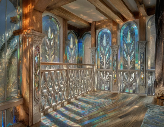 A wooden room with carved railings by iridescent stained glass windows casting curving shadows on a hardwood floor.