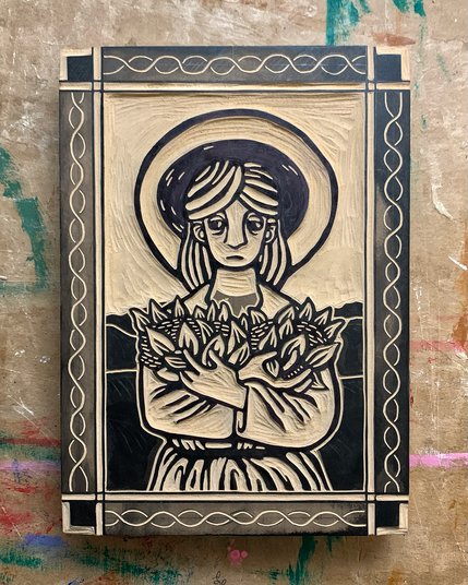 Photo of a carved linoleum block. Design is a frontal view of a medieval farmer holding plants in his arms. The farmer has a halo and is surrounded by a patterned border.