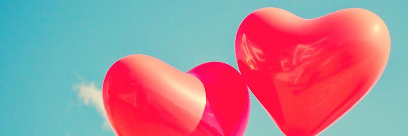 Zwei rote Herzen in Luftballonform vor einem türkisblauen Himmel