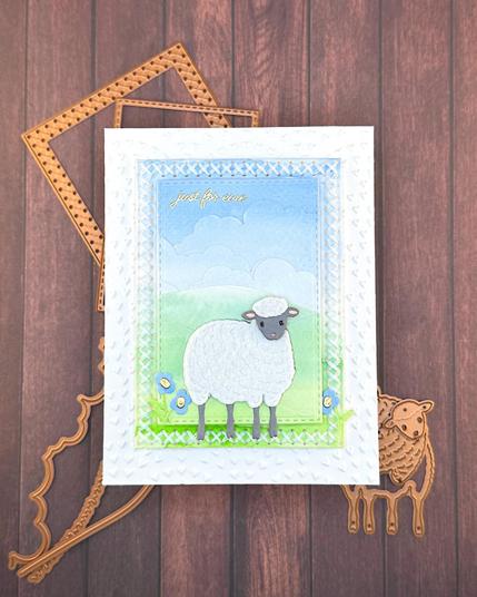 Greeting card in soft blue and green tones. The focus is a sheep with the body done in white felt. The greeting reads "Just for ewe."