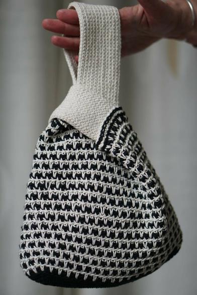 Hand holding up a crochet bag black and white.