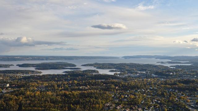A photo of the Oslofjord viewed from a hilltop. The sky is filled with clouds.