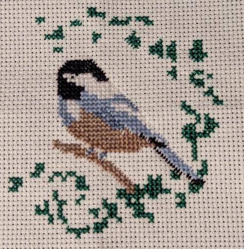 Chickadee on a branch is now surrounded by small blobs of emerald green.